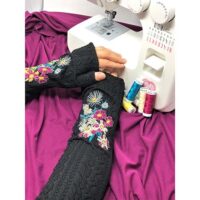 A person with their hands on the arm of a sewing machine.