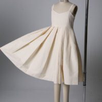 A dress is shown on display in front of a white background.